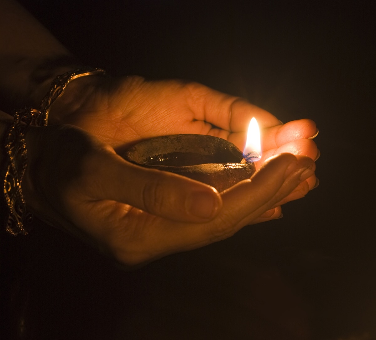 Two hands holding a Diwali light