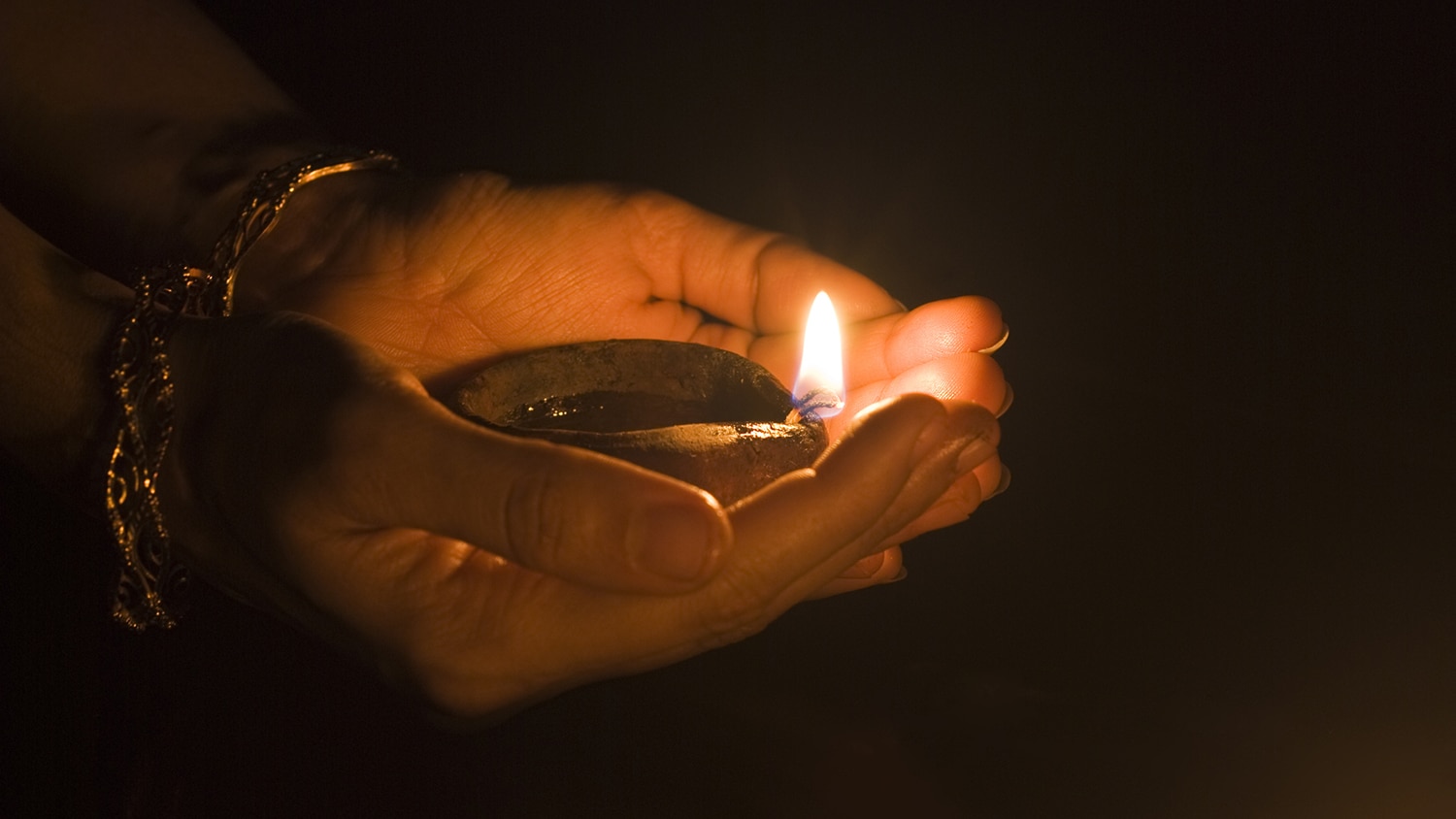 Two hands holding a small Diwali light